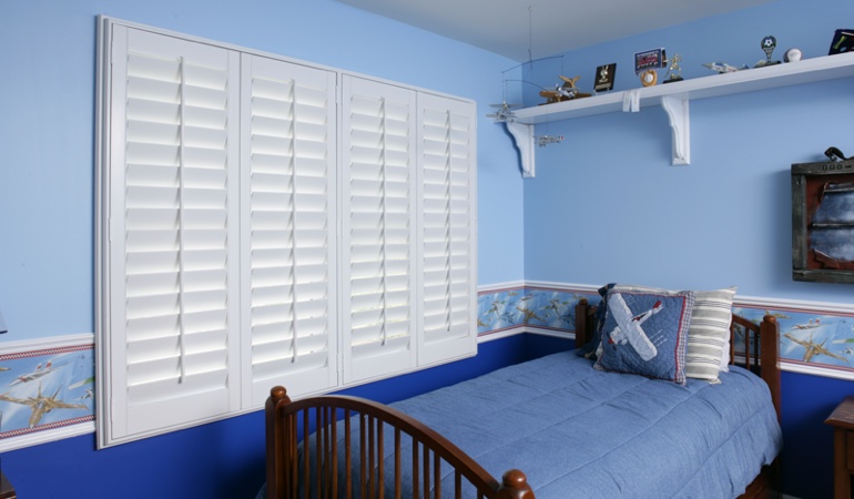 Large plantation shutters covering window in blue kids bedroom in Atlanta 